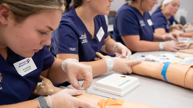 护理 students practicing injections into fake arms